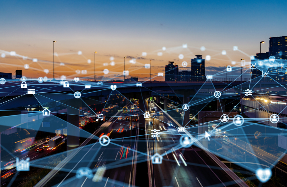 Smart city network concept overlaid an image of highway traffic moving through a large city at dusk.