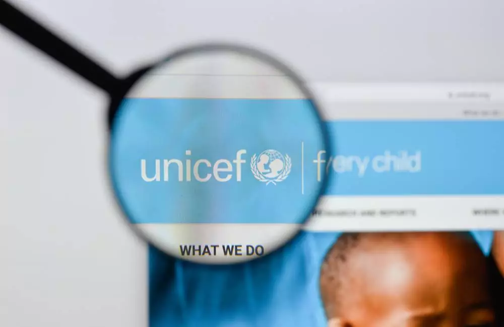 A magnifying glass magnifies the UNICEF logo on a website page.