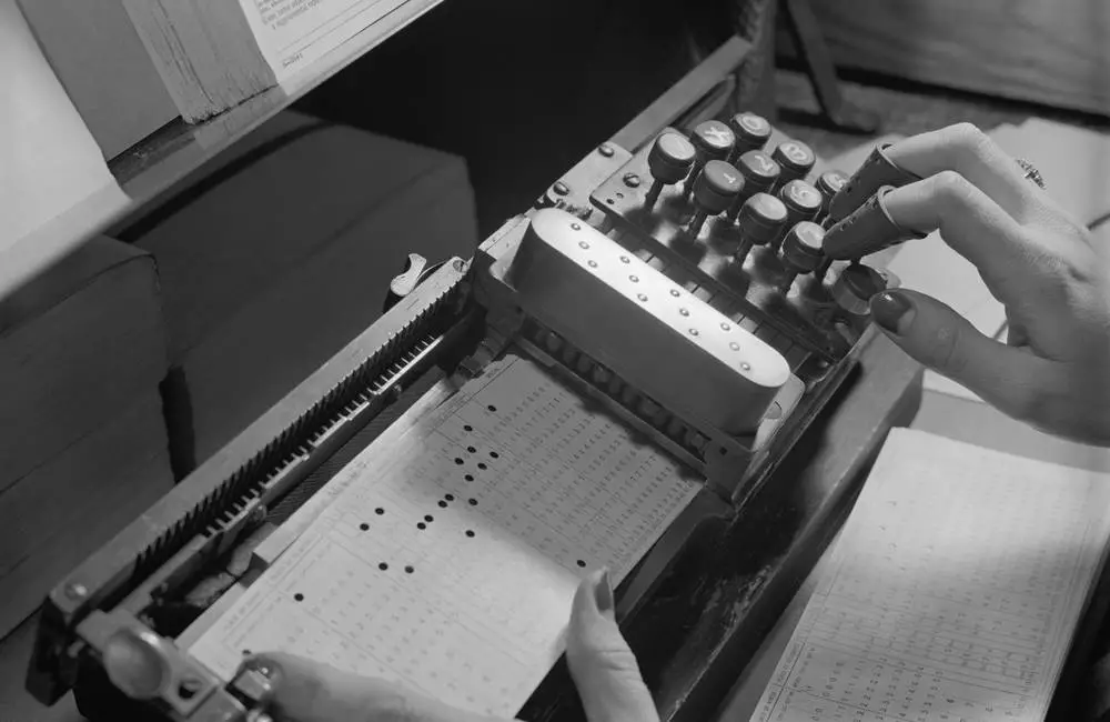 A black and white photo of someone typing on an old device.